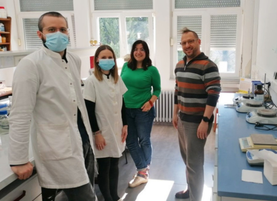 four people, some in lab coats, in lab, looking at camera, smiling. One of them is Founder Marko Vincekovic