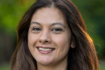 woman with brown hair smiling into the camera.