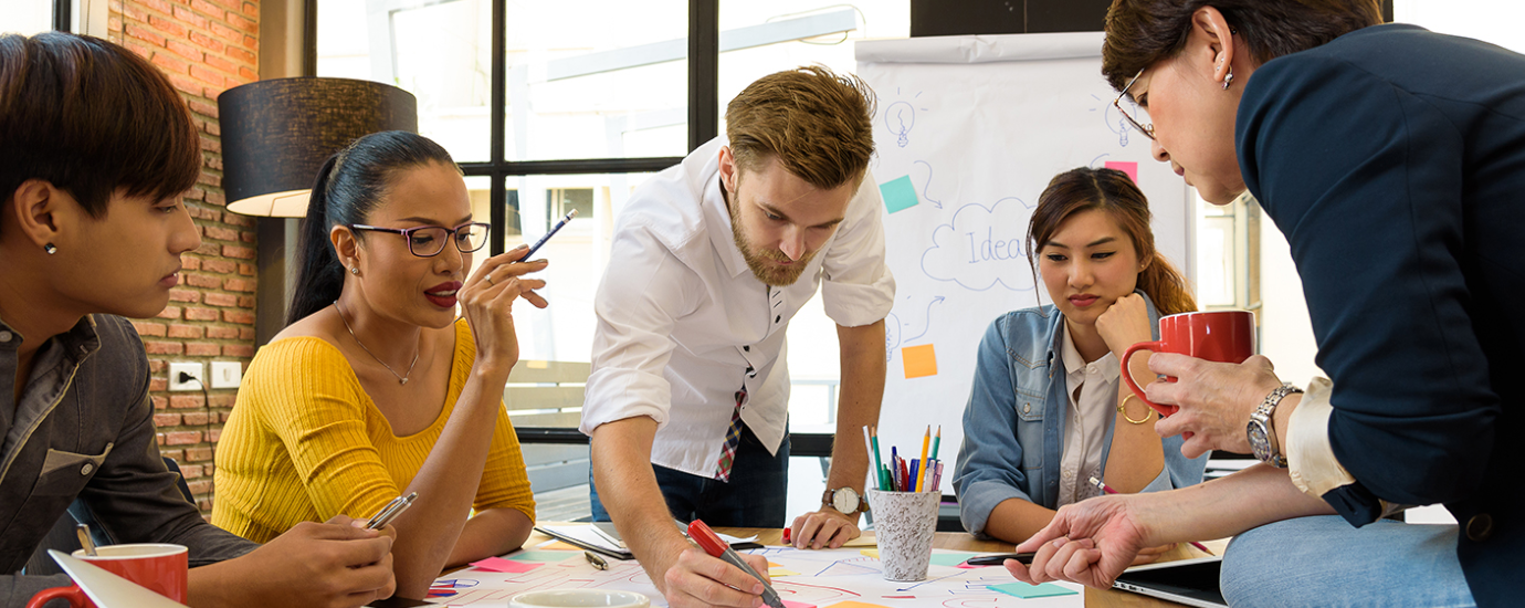 A group of young people are discussing around an office table, brainstorming.