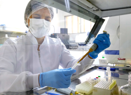 woman in protective clothes transfering a liquid at a fume cupboard in the laboratory