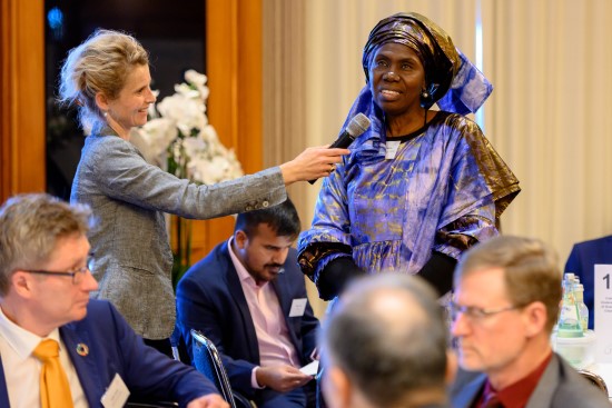 Woman from the audience talking at a conference while another woman ist holding the microphone