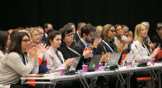 A group of people sitting in an audience and clapping.