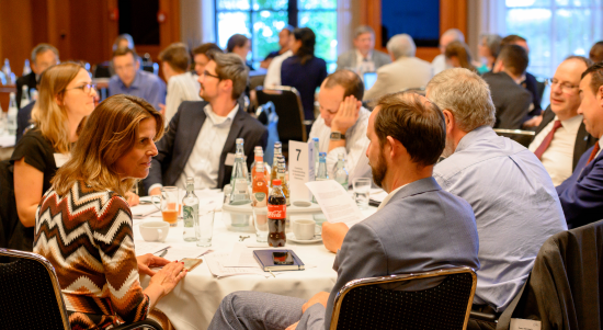 A group of conference participants at a table in discussion