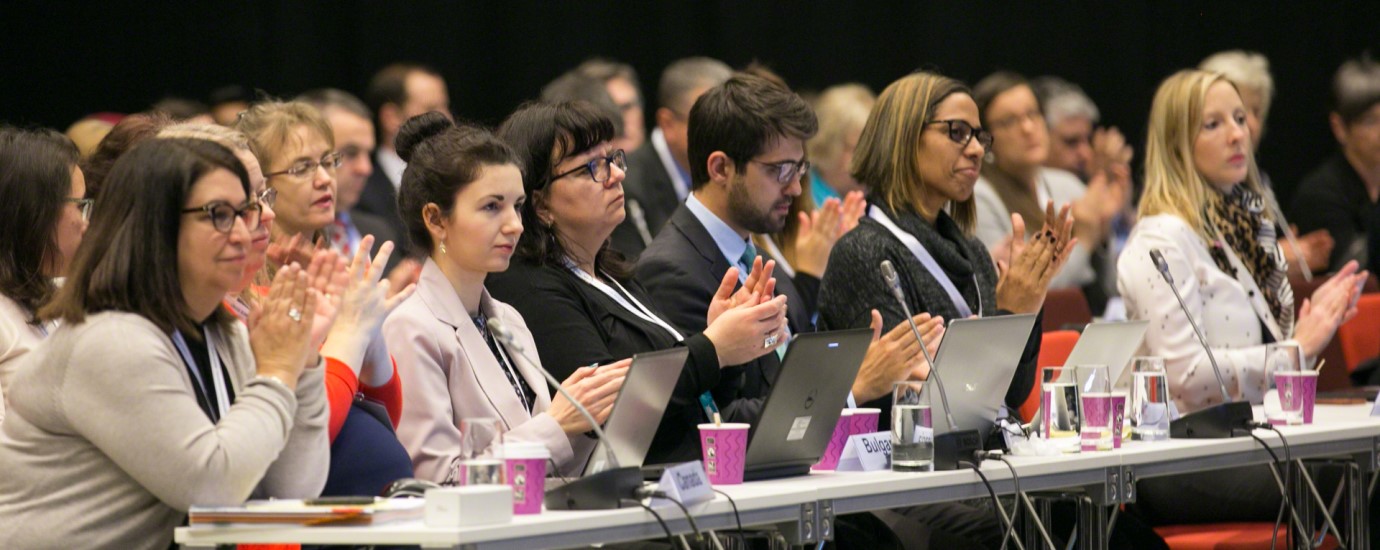 A group of people sitting in an audience and clapping.