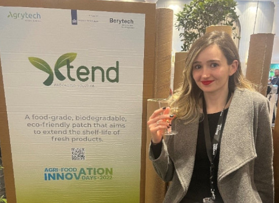 Rachel Sfeir, co-founder and R&D manager standing in front of her start-up poster at a trade fair