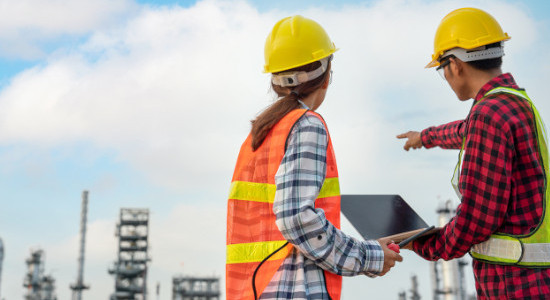 a woman and a man in protective clothes looking at a power plant