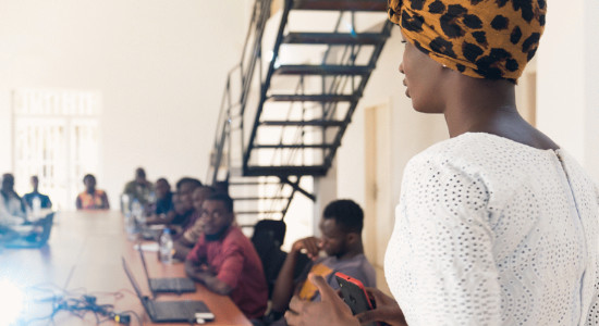 black woman presenting to a group of people facing the beamer.