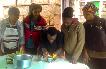 man lighting fire in a can, while four women are watching