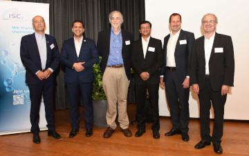 a group of six men pose for a photo in front of an ISC3 banner