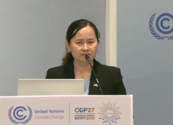 Woman standing at a desk holding a speech.