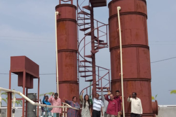 a group of people in front of a red industrial chimney