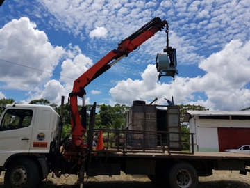 a crane lifting a machine from a truck