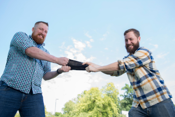 two men holding a piece of material outdoors