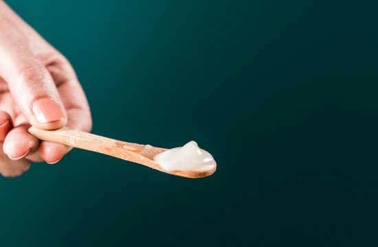 a hand holding a wooden spoon with a creamy substance