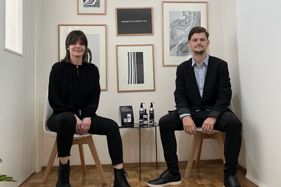 a man and a woman sitting on chairs smiling at the camera