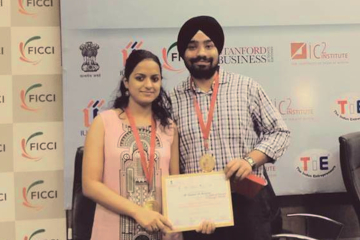 two persons looking at the camera holding a certificate