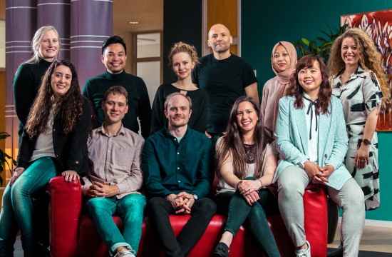 a group of eleven people sitting on a big red couch