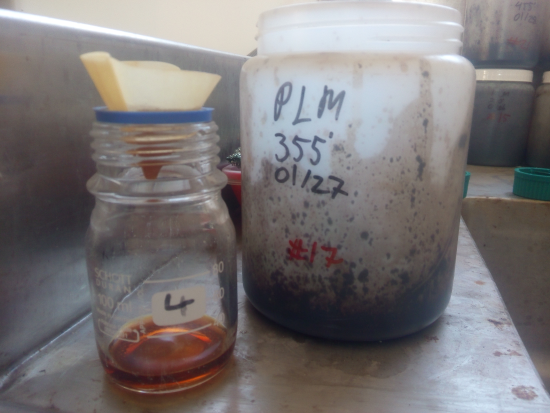 a container filled with a small amount of filtered liquid and another container with solid waste