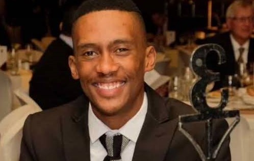 a young man in a suit smiling at the camera