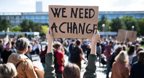  Woman holding a sign stating "We need change" 