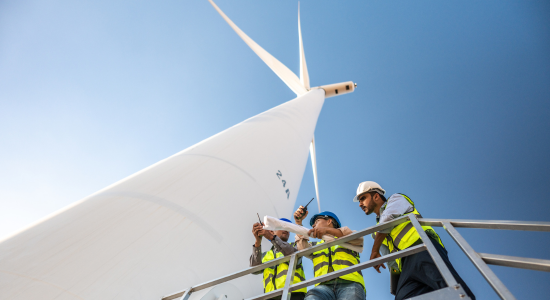 three men standing below a windmill