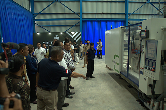 a group of perople watches a guide explaining a machine