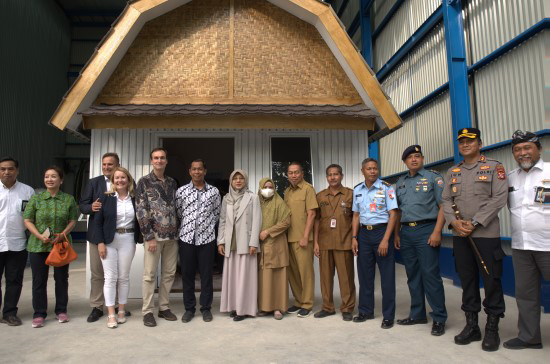 a group of people standing indoors in front of a house prototype