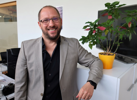 man with glases in a suit looking at camera, smiling