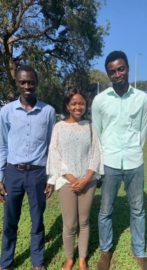 two black men and one black woman in the middle smiling at the camera.