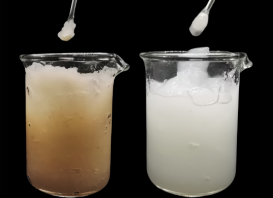 two beakers with paste like content inside in front of a black background. One beaker with white substance, the other with yellowish substance