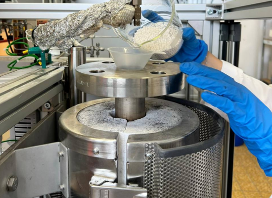 A round metal reactor is filled with white pebbles