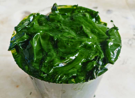 A bucket full of green slime, looking like gelanitous sheets