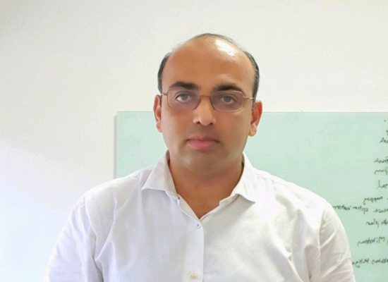 Indian man with glasses looking into camera, white background