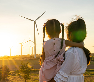 Woman with daughter looking on a fild with wind turbines